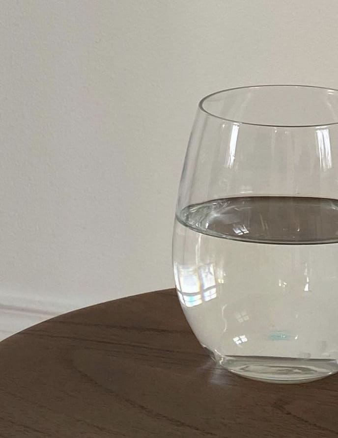 Vaso de agua sobre una mesa de madera, con luz natural.