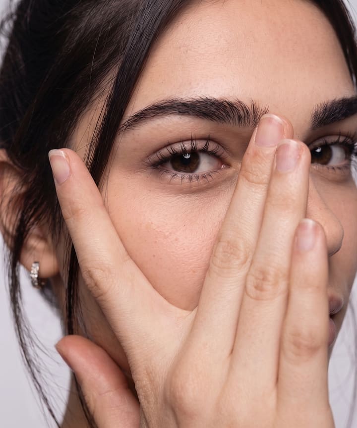Modelo apoya la mano con suavidad sobre su rostro.
